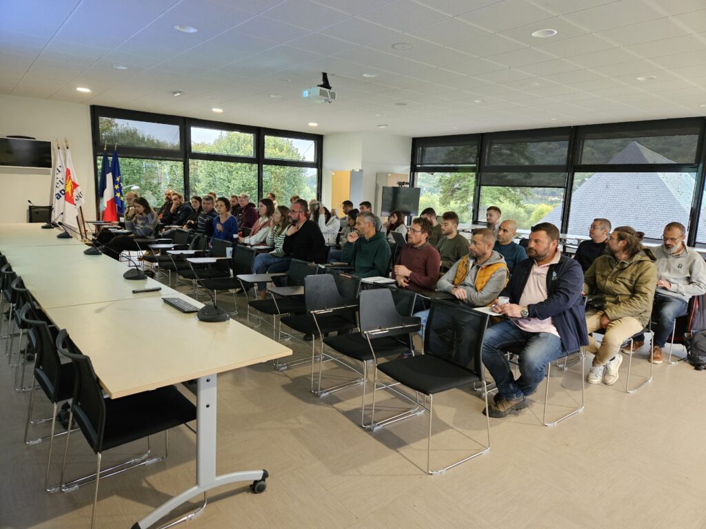 Groupe de personnes assises dans une salle et écoutant un intervenant